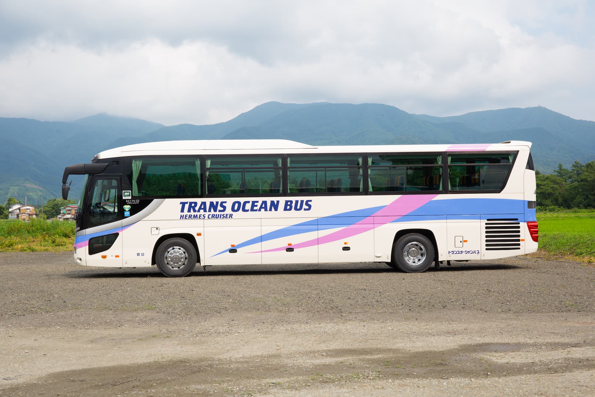 山形の風景を背景に停車するトランスオーシャンバスの大型観光バス